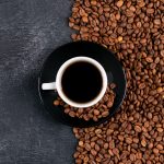 xicara de cafe vista superior e graos de cafe na mesa escura