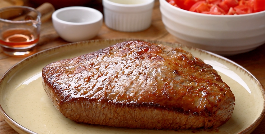 Brisket suculento selado em um prato, ideal para um almoço delicioso, acompanhada de temperos e ingredientes frescos.